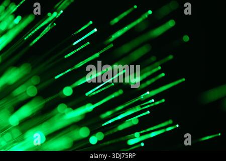 Abstrakte grüne Lichtstreifen auf dunklem Hintergrund, leuchtende Bokeh-Linien symbolisieren Datenfluss und Technologie Stockfoto