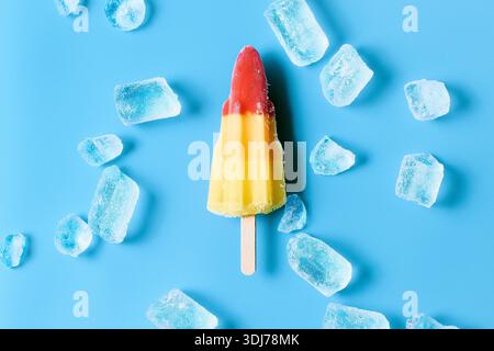 Farbenfrohe Rocket Ice Lolly auf blauem Hintergrund mit Eiswürfeln Stockfoto