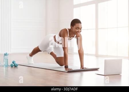 Fröhliche Afro-Frau Beim Training Von Cross Body Mountain Kletterern Stockfoto