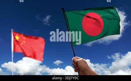 Bangladesch-Flagge winkt unter Wolken. Fliegen Sie in den Himmel. Foto der chinesischen Flagge mit absichtlich verschwommenem Hintergrund Stockfoto