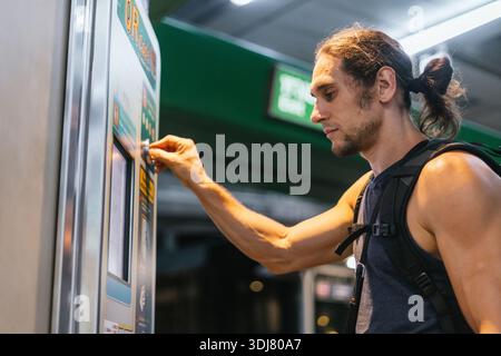 Mann, der am Automaten Fahrkarten für öffentliche Verkehrsmittel kauft Stockfoto