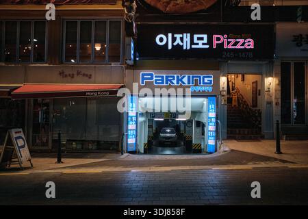 Busan, Südkorea: Nächtliche Straßenszene mit beleuchteten koreanischen Restaurantschildern und Parkeingang in der Innenstadt von Busan Stockfoto