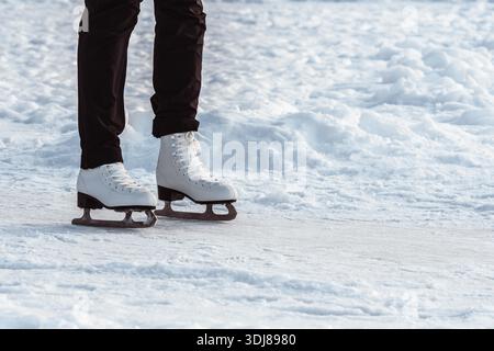 Nahaufnahme eines Mädchens, das draußen Schlittschuhlaufen zeigt, wie weiße Eisfiguren im Winter über schneebedecktes Eis gleiten Stockfoto