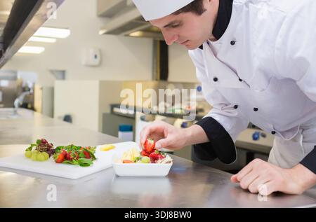 Erdbeeren und Trauben werden auf Metall-Vorbereitungstheke in der kommerziellen Küche, Kopierraum angeordnet. Veredelung, Obst, Beilage, Nahaufnahme, Koch, rostfrei, Stockfoto