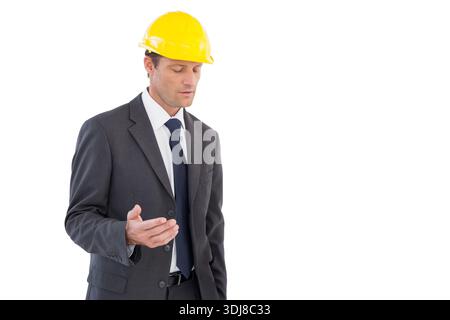 Ein reifer Mann steht links im Studio mit dunklem Anzug und gelbem Schutzhelm, Kopierraum. Professionell, Corporate, Hardhat, Porträt, minimalistisch, monoc Stockfoto