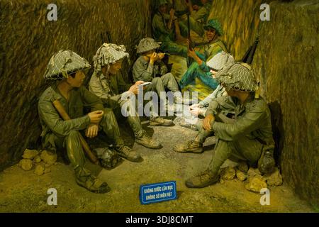 Dien Bien Phu, Vietnam - 4. September 2022: Wachsfiguren in Militäruniformen mit Netzhelmen werden im Dien Bien Phu Museum in einem Grabendiorama mit Gewehren und einem gemalten Wandbild weiterer Soldaten dargestellt. Stockfoto