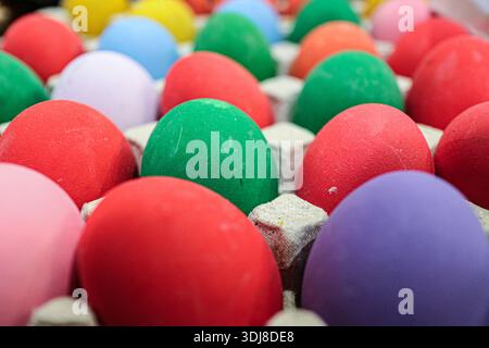 Bunte Auswahl an bunten gefärbten Eiern in einem Karton. Steht für Vielfalt und festliche Feier. Moderne Osterstilleben-Hintergrund. Stockfoto