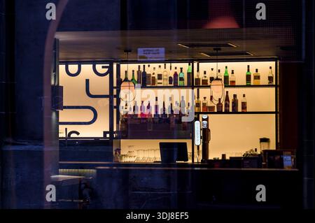 Nachts durch ein Fenster zu einer leeren Bar und Gantry schauen, Großbritannien Stockfoto