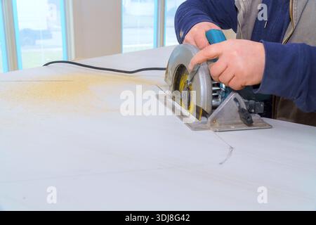 Handlich man bedient die Kreissäge auf der Werkbank beim Schneiden des Materials in der Werkstatt Stockfoto