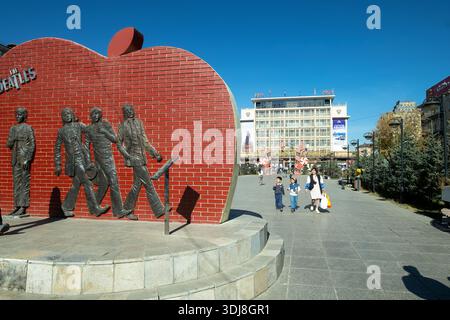 Beatles Monument auf dem Stadtplatz von Ulaanbaatar, wo Menschen an einem sonnigen Tag spazieren gehen, Mongolei Stockfoto