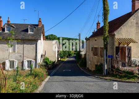 Unbekannte Lage - 29. Juni 2022: Eine ruhige Wohnstraße gesäumt von traditionellen Häusern mit Fensterläden, Schornsteinen und sichtbaren Straßenschildern unter einem klaren blauen Himmel. Stockfoto