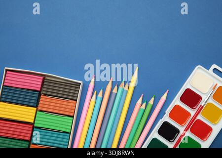 Farbstifte, Plastilin und Aquarellfarben auf dunkelblauem Hintergrund. Draufsicht Stockfoto