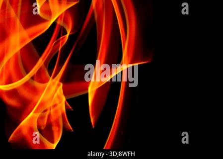 Leuchtende Flammen-ähnliche Lichtspuren bilden energetische abstrakte Bewegungen auf schwarzem Hintergrund. Stockfoto
