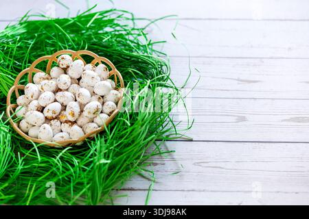 Goldene und weiße Ostereier in einem Nest mit grünem Gras auf hölzernem Hintergrund. Geometrie. Das Minimalkonzept von Ostern. Draufsicht. Eine Osterkarte mit einem Stockfoto