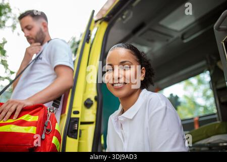 Multiethnische Sanitäter stehen vor einem Krankenwagen. Notarzt und Krankenschwester stehen vor dem Krankenwagen Stockfoto