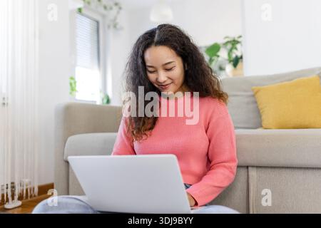 Asiatische Frau, die mit Computer auf dem Sofa sitzt, zu Hause studiert, E-Learning und freiberufliches Jobkonzept Stockfoto