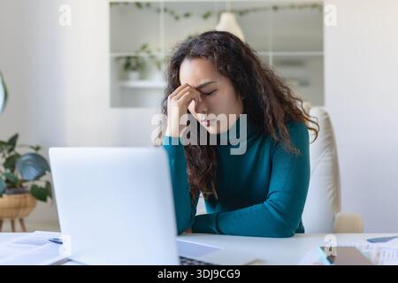 Erschöpfte asiatische Geschäftsfrau, die Kopfschmerzen im Büro hat. Kreative Frau, die am Schreibtisch arbeitet, fühlt sich müde. Gestresstes, zwangloses Geschäftsgefühl Stockfoto
