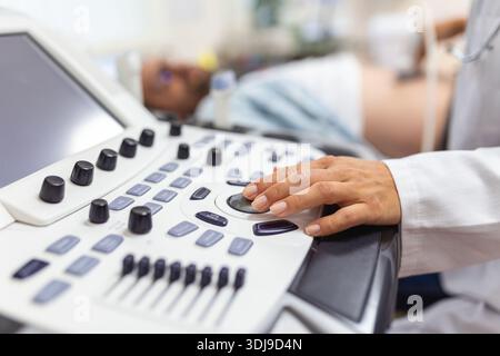 Geschickter Sonograf mit Ultraschallgerät bei der Arbeit. Mann, der seinen Arzt zur Ultraschalluntersuchung besucht. Professionelle ärztliche Sonografin im Auftritt Stockfoto