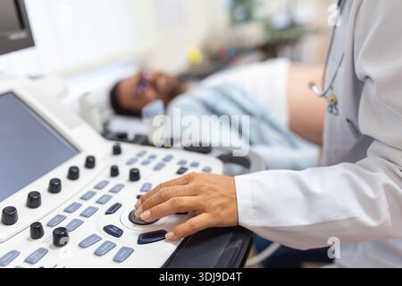 Geschickter Sonograf mit Ultraschallgerät bei der Arbeit. Mann, der seinen Arzt zur Ultraschalluntersuchung besucht. Professionelle ärztliche Sonografin im Auftritt Stockfoto