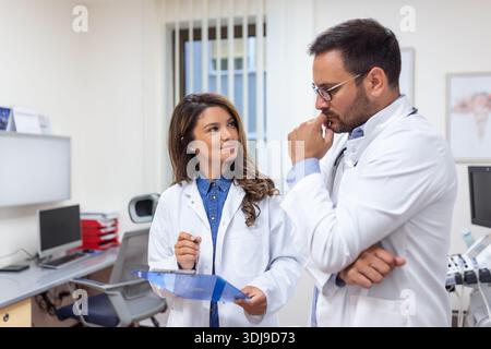 Ärzte diskutieren über einen medizinischen Bericht im Krankenhaus. Ärztin und Ärztin überprüfen online den klinischen Patientenbericht. Gesundheitspersonal mit Disku Stockfoto