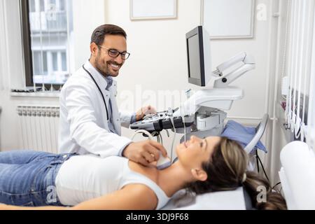 Ultraschalldiagnostik der Schilddrüse der Frau in der Klinik, Arzt führt Ultraschallsensor. Junge Frau, Die Neck Ultraschall Untersuchung In Hospi Macht Stockfoto