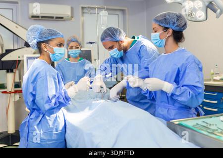 Dringende Operation. Professionelle smart intelligent Chirurgen stehen in der Nähe des Patienten und die Durchführung einer Operation während seinem Leben speichern Stockfoto