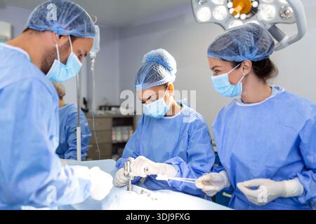 Dringende Operation. Professionelle smart intelligent Chirurgen stehen in der Nähe des Patienten und die Durchführung einer Operation während seinem Leben speichern Stockfoto
