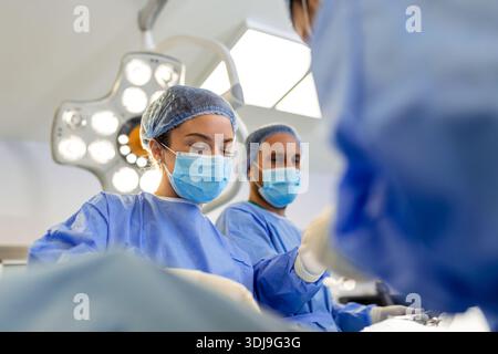 Gruppe von Chirurgen bei der Arbeit im Operationssaal in blau getönt. Ärzteteam Tätigkeit Stockfoto