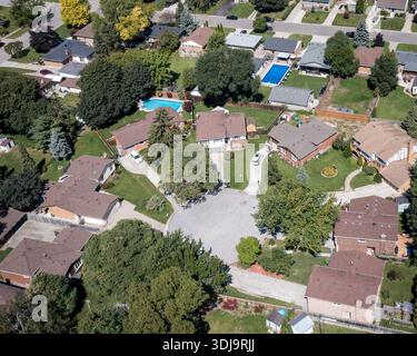 Drohnenantenne einer Sackgasse vor Ort mit Wohnhäusern, von Bäumen gesäumten Straßen und Schwimmbädern im Hinterhof. Stockfoto