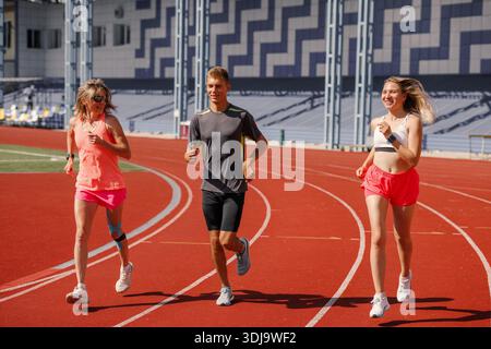Gruppe von jungen Athleten laufen auf Stadionbahn Outdoor Fitness Training Teamwork gesunde Lebensweise Sommer Sport Stockfoto
