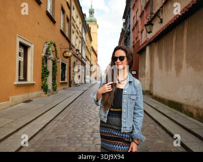 Eine Frau, die in legerer Kleidung auf der alten europäischen Straße läuft Stockfoto