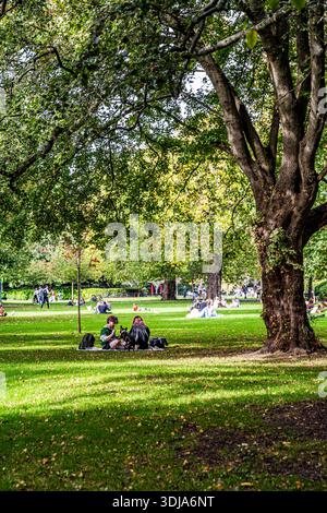 St Stephen’s Green mit Menschen, die sich auf dem Gras entspannen, friedliche Atmosphäre in einem der beliebtesten historischen Parks der Stadt, Dublin, Irland. Stockfoto