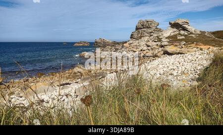 Zerklüftete Küste mit großen Felsbrocken, offenem Meer und wilder Vegetation entlang der Küste, natürliche und ungezähmte Landschaft. Stockfoto