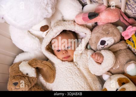 Baby spielt mit Plüschspielzeug in einem gemütlichen Kinderbett Stockfoto