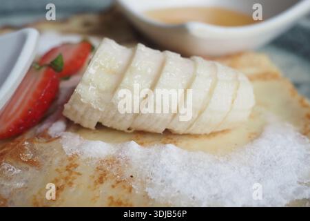 Bananen- und Erdbeerdessert mit süßer Sauce auf Teller Stockfoto