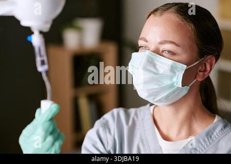 Kaukasische junge Erwachsene Frau Krankenschwester, die intravenösen Tropf im Krankenhaus einstellt Stockfoto