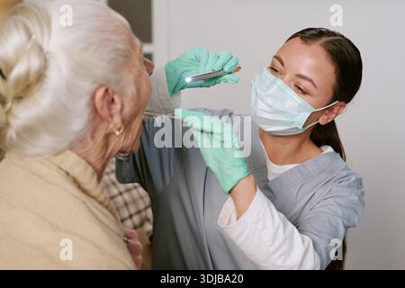 Junge kaukasische Krankenschwester untersucht ältere kaukasische Frau in der Klinik Stockfoto