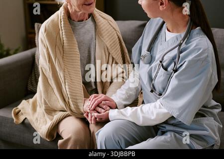 Junge Erwachsene Kaukasische Krankenschwester, Die Hände Hält, Um Seniorinnen Zu Trösten Stockfoto