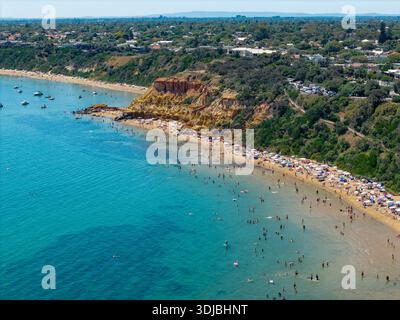 Ein Luftbild zeigt Blackrock Beach mit zahlreichen Menschen, die im klaren blauen Wasser schwimmen und sich am Sandstrand entspannen. Stockfoto