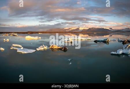 Ein Blick auf die Eisberge und die Lagune des Jokulsarlon-Gletschers mit dem Vatnajokull-Gletscher im Hintergrund bei Sonnenaufgang Stockfoto
