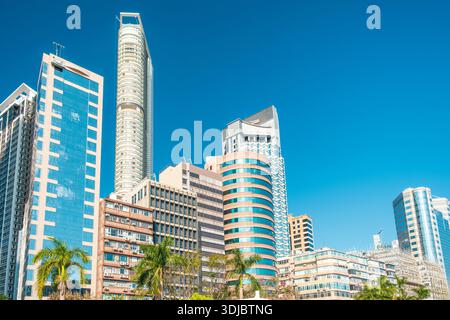Moderne Wolkenkratzer und Wohngebäude unter klarem blauem Himmel im Kowloon District, Hong Kong City mit Palmen, China. Globale Stadt, Urban Stockfoto