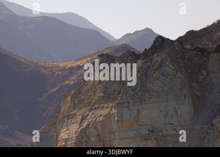 Ein atemberaubender Blick auf die zerklüfteten, mehrschichtigen Berge auf der Arabischen Halbinsel, getaucht im weichen, warmen Licht von Sonnenaufgang oder Sonnenuntergang. Die Vordergrundleistung Stockfoto