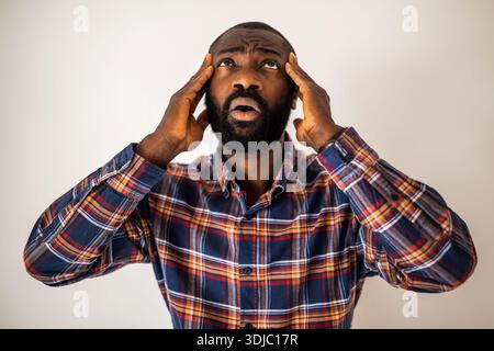 Porträt eines emotional gestressten, verwirrten und schockierten Schwarzen, der aufblickt und den Kopf hält. Stockfoto