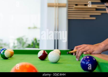 Mann, der den CUE-Stick in Richtung CUE-Ball auf dem Billardtisch positioniert, Kurzarmhemd, Kopierraum Stockfoto
