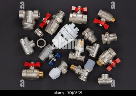 Wasserkugelventil mit Anschlussstück und Thermostatventilkopf auf Rindenhintergrund. Stockfoto