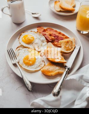 Nahaufnahme eines Tellers mit Speck, Eiern, Toast und Getränken zum Frühstück. Stockfoto