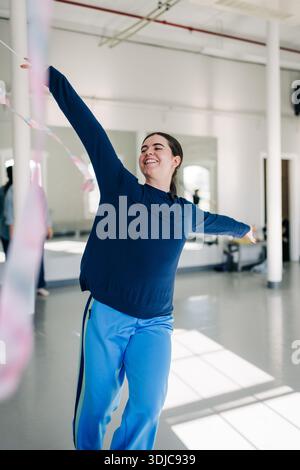 Lächelnde Frau tanzt mit bunter Schleife im Studio Stockfoto