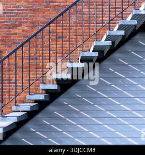Nahaufnahme einer Außentreppe aus Metall und einer Ziegelwand Stockfoto