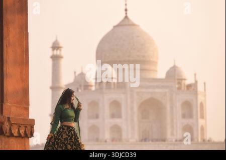 Seitenansicht einer jungen Frau in einem Sari vor dem Taj Mahal bei Sonnenuntergang, Agra, Uttar Pradesh, Indien, Stockfoto