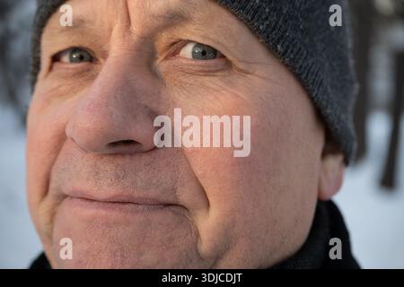 Nahaufnahme Porträt eines Reifen Mannes, der draußen Wintermütze trägt. Natürliches Altern, Charakter und winterliches Lifestyle-Konzept. Stockfoto